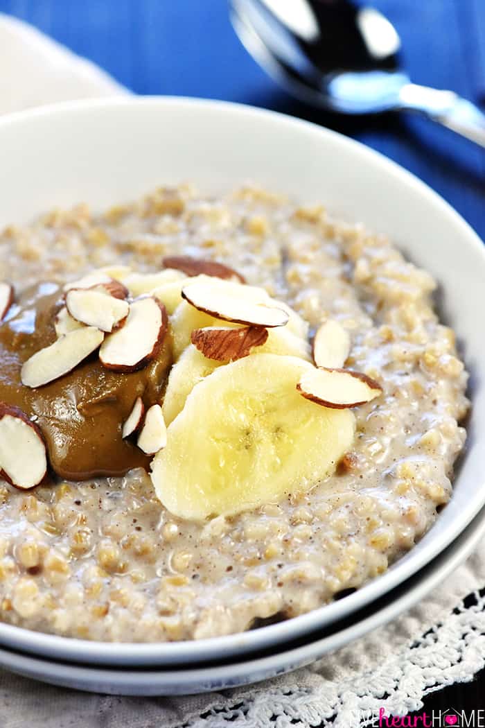 Bowl of Steel Cut Oats topped with bananas, peanut butter and slivered almonds.