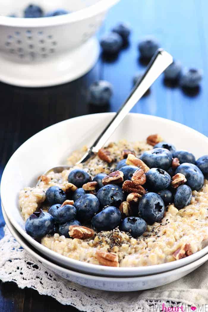 Steel cut oats in a bowl topped with fresh blueberries and pecans.