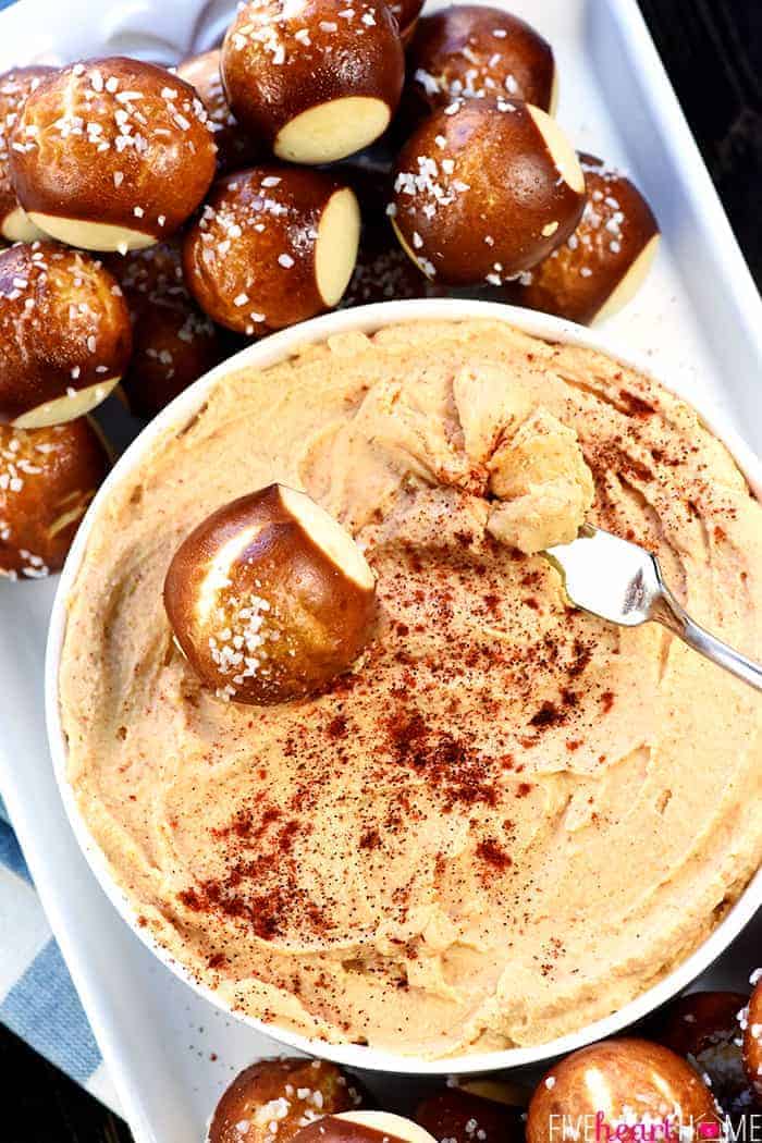 Bowl of Cheese Dip on platter with soft pretzel bites for dipping.