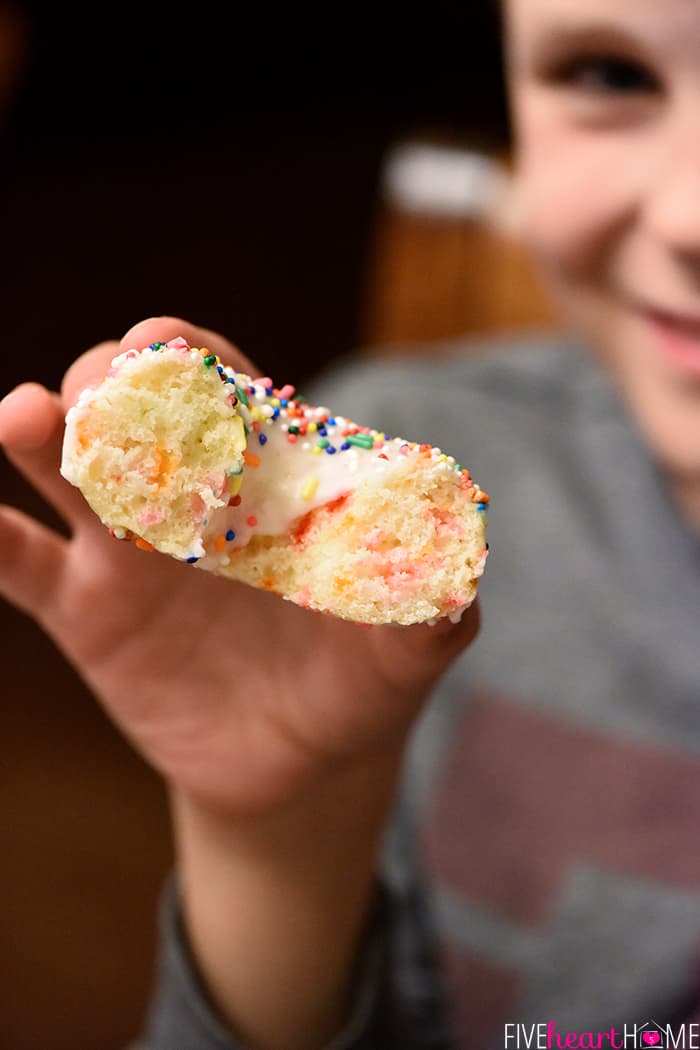 Boy holding half-eaten doughnut.