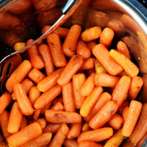 Aerial view of Instant Pot Carrots in pressure cooker with serving spoon.
