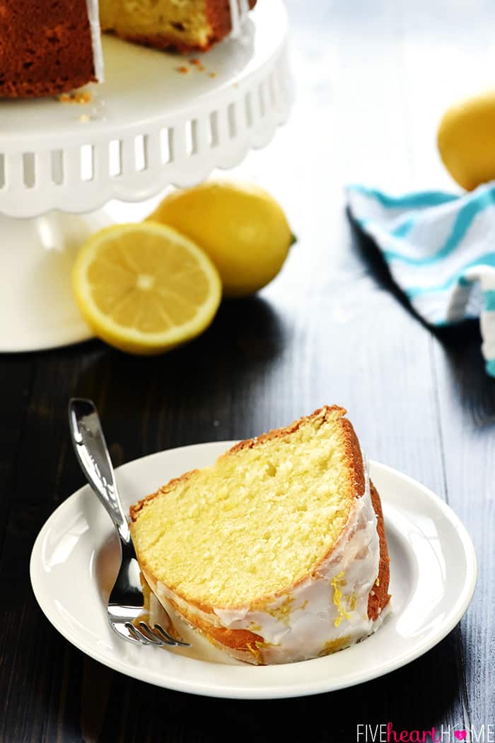 Lemon Pound Cake slice on plate with cake stand in background.