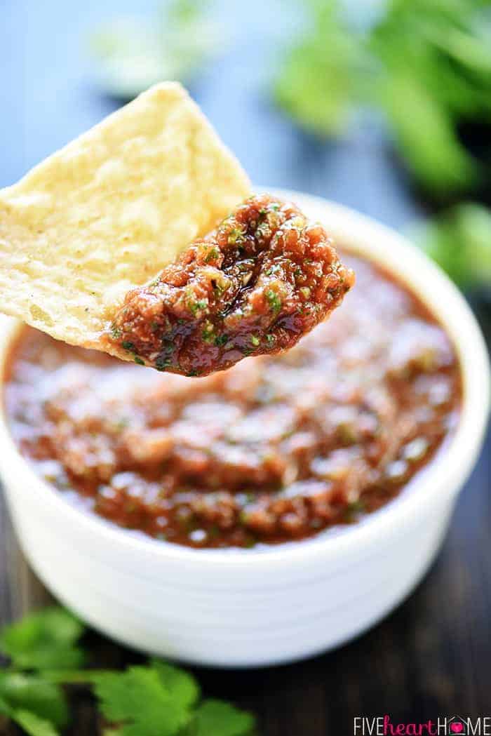 Chip hovering over bowl with a big dip of salsa recipe.