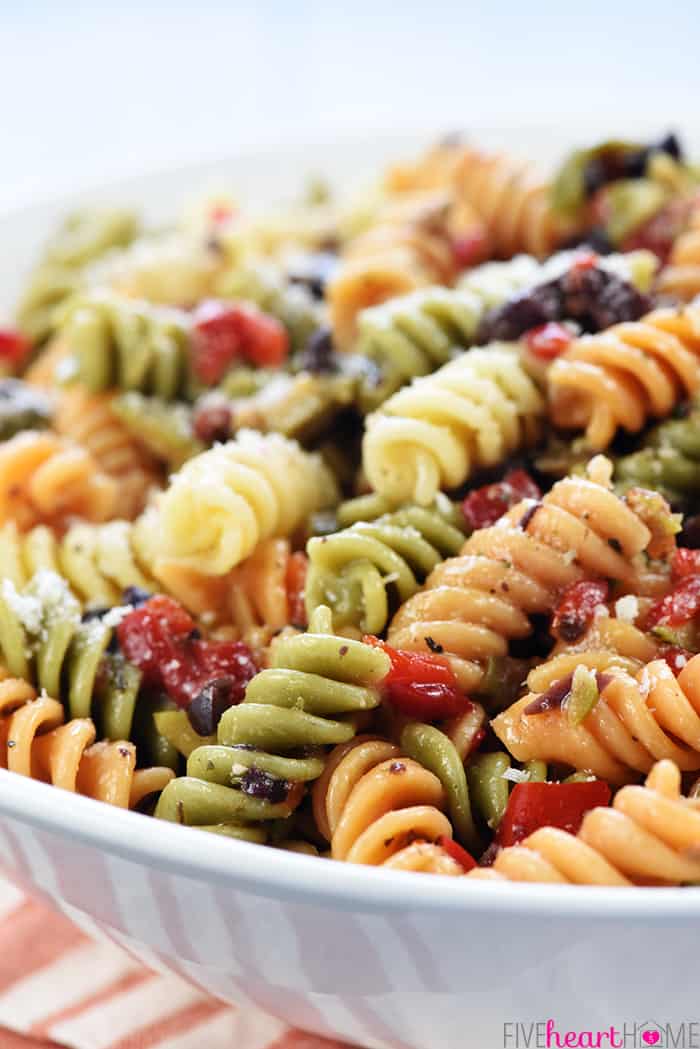 Easy Pasta Salad ~ tri-color garden rotini is studded with diced olives and pimentos, tossed with a zesty homemade Italian dressing, and showered with Parmesan for a versatile summer side dish recipe! | FiveHeartHome.com Close-up of pasta, olives, pimentos, parmesan, and Italian dressing.