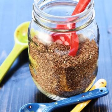 Homemade Taco Seasoning in mason jar with ceramic measuring spoons.