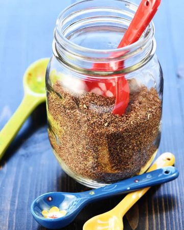 Homemade Taco Seasoning in mason jar with ceramic measuring spoons.