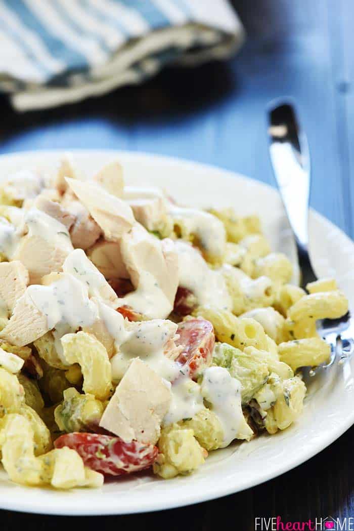 Cobb Pasta Salad ~ loaded with bacon, avocado, tomatoes, hard-boiled eggs, cheese, and homemade ranch dressing, this is the perfect recipe for summer picnics, potlucks, parties, and barbecues! | FiveHeartHome.com Cobb Pasta Salad on plate with sliced chicken over top.