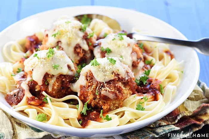 Chicken Parmesan Meatballs over pasta in a bowl.
