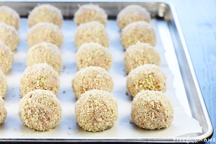 Chicken Parmesan Meatballs ~ a ground chicken mixture is formed into meatballs, rolled in Panko and Parmesan, baked, and then covered in flavorful marinara sauce and melted mozzarella...perfect for serving as an appetizer, over pasta, or on subs! | FiveHeartHome.com Lined up on baking sheet, ready to go into ove.