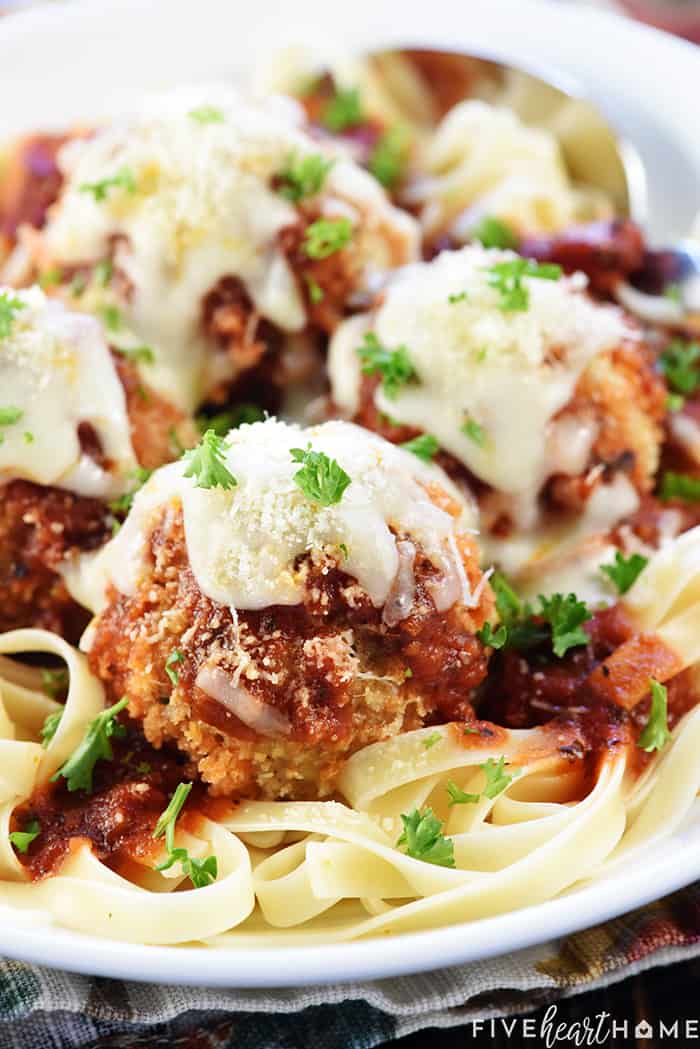 Chicken Parmesan Meatballs ~ a ground chicken mixture is formed into meatballs, rolled in Panko and Parmesan, baked, and then covered in flavorful marinara sauce and melted mozzarella...perfect for serving as an appetizer, over pasta, or on subs! | FiveHeartHome.com Chicken Parmesan Meatballs served over pasta.