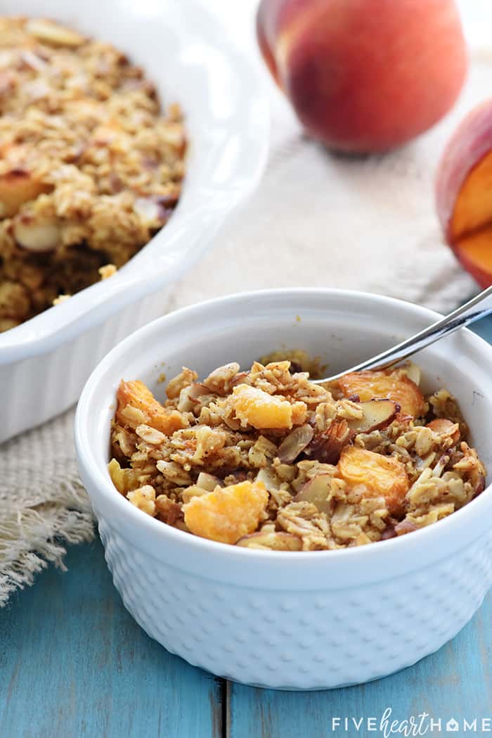 Peach Baked Oatmeal in bowl with fresh peaches in background.