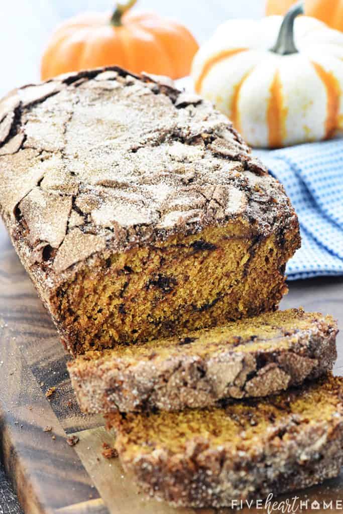 Snickerdoodle Pumpkin Bread recipe, sliced with pumpkins in background.