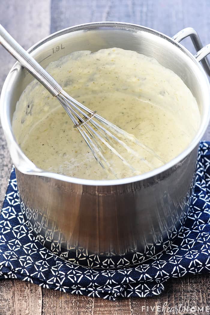 White Queso being melted and mixed in a pot.