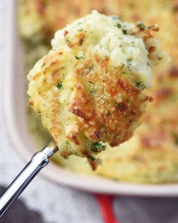Make Ahead Mashed Potatoes, serving spoon held over dish.