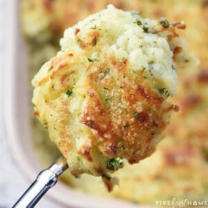 Make Ahead Mashed Potatoes, serving spoon suspended over baking dish.