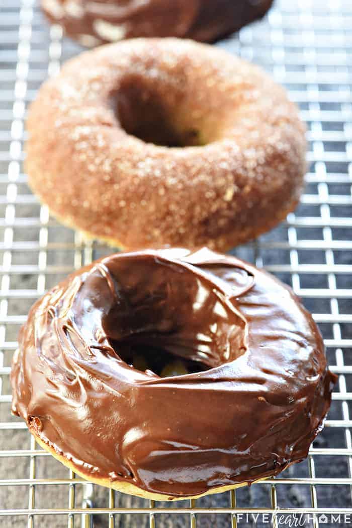Baked Banana Donuts ~ soft, sweet, lightened-up, and easy to make, with your choice of a decadent chocolate glaze or a coating of cinnamon sugar! | FiveHeartHome.com Baked Banana Donuts on a wire cooling rack