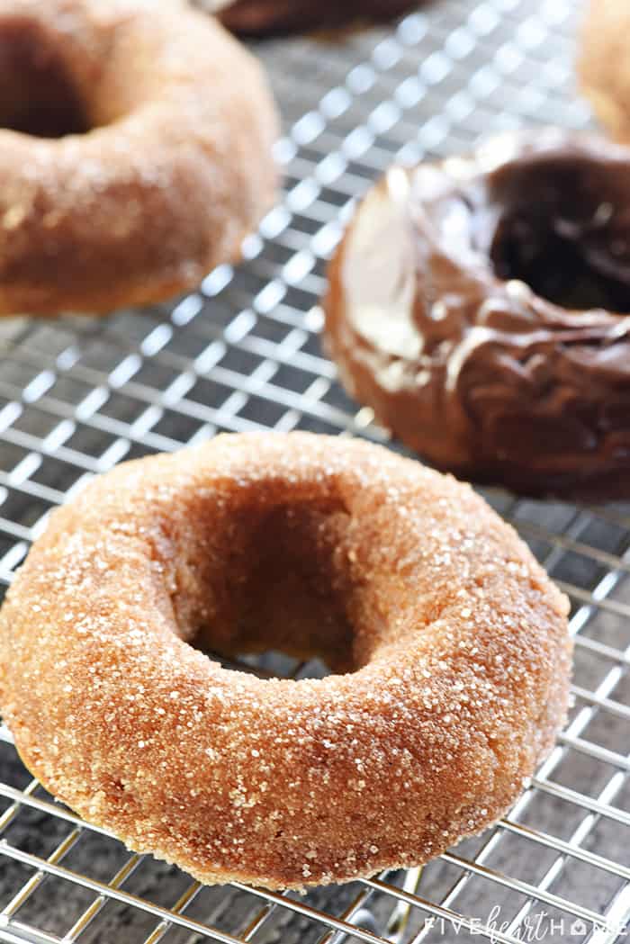 Baked Banana Donuts ~ soft, sweet, lightened-up, and easy to make, with your choice of a decadent chocolate glaze or a coating of cinnamon sugar! | FiveHeartHome.com Banana Baked Donuts on a wire rack, some with cinnamon sugar and some with chocolate glaze
