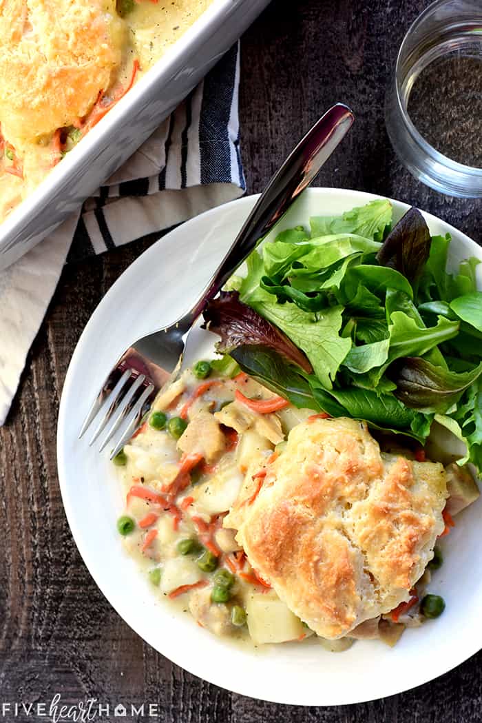 Chicken Pot Pie Casserole ~ this easy comfort food recipe features a classic filling of tender chicken, potatoes, carrots, and peas in a savory gravy topped with fluffy homemade drop biscuits! | FiveHeartHome.com Aerial view of Chicken Pot Pie Casserole on a plate with a salad.
