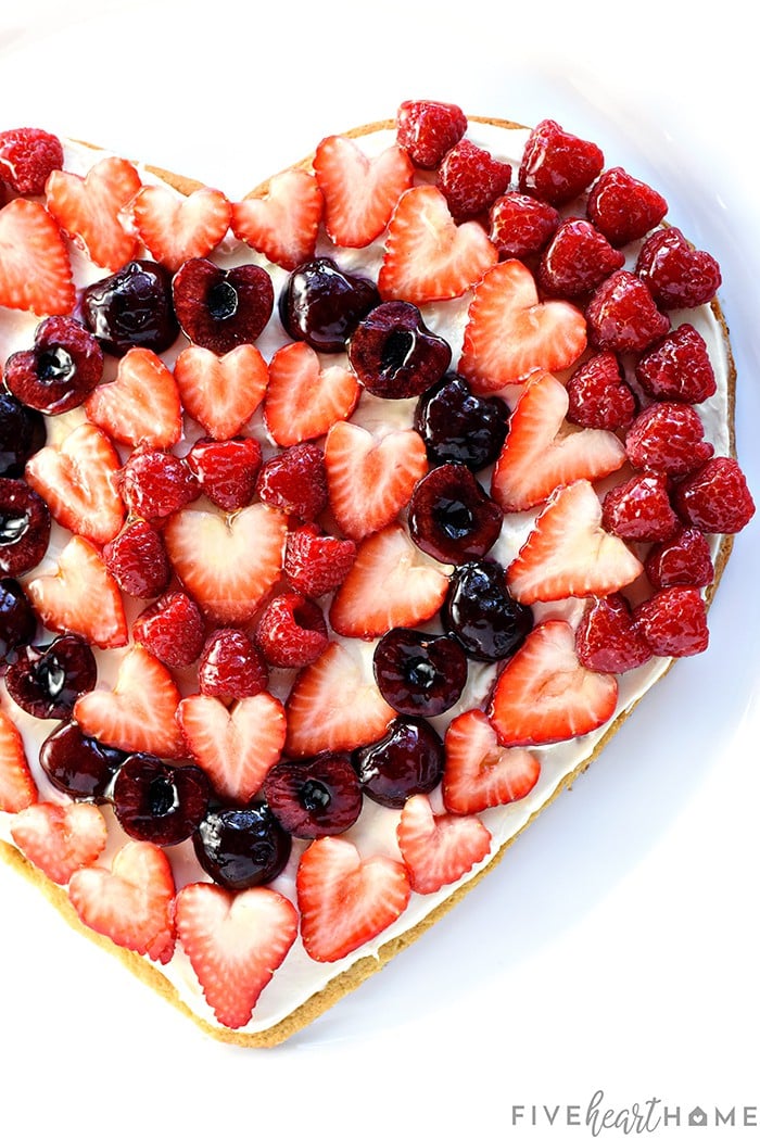 Fruit Pizza ~ on a heart-shaped sugar cookie crust, this fruit pizza features cream cheese frosting topped by glossy berries & cherries. It's a perfect Valentine's Day dessert or treat for any occasion! | FiveHeartHome.com.com Aerial photo of heart-shaped Fruit Pizza with berries.