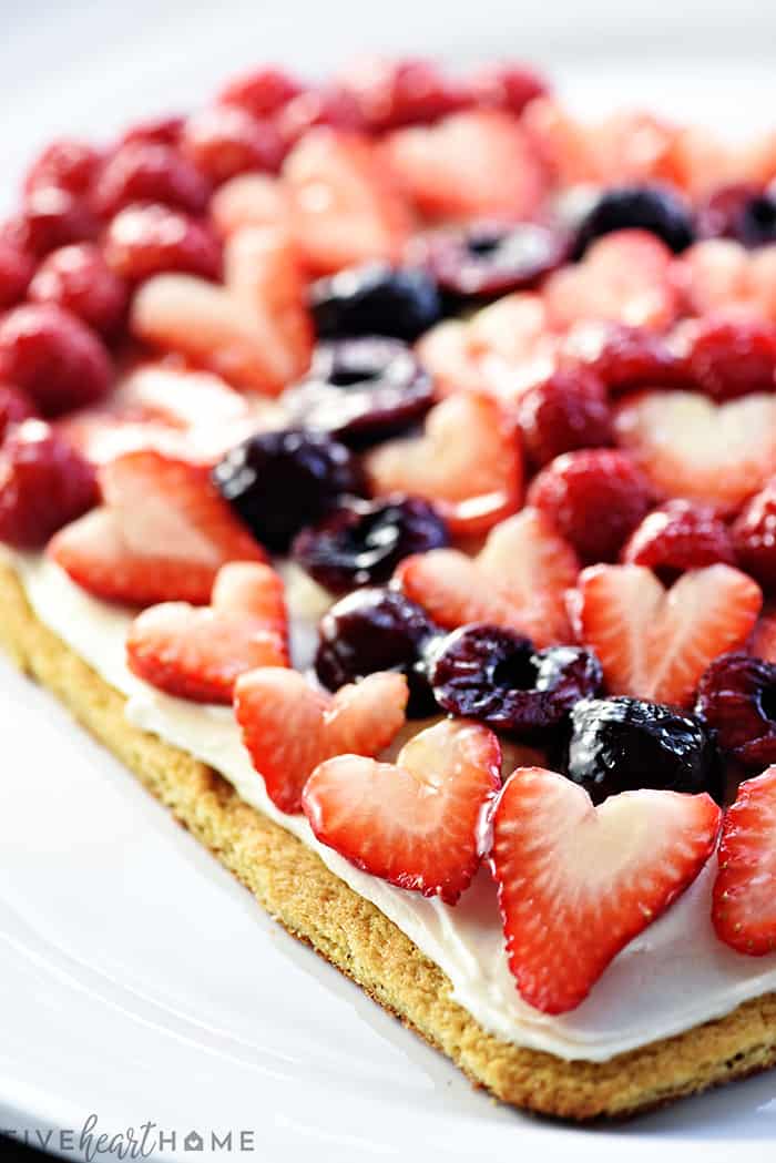 Fruit Pizza ~ on a heart-shaped sugar cookie crust, this fruit pizza features cream cheese frosting topped by glossy berries & cherries. It's a perfect Valentine's Day dessert or treat for any occasion! | FiveHeartHome.com.com Close-up of Fruit Pizza.
