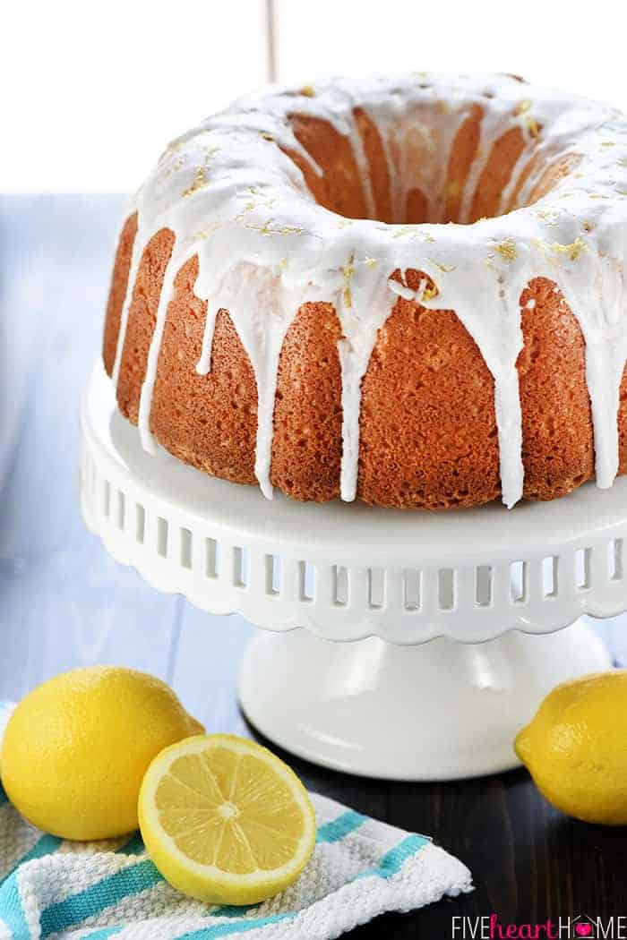 Homemade Lemon Pound Cake on cake stand with fresh lemons on table.
