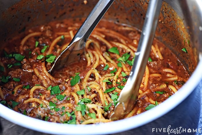 Easy spaghetti recipe in a pot, ready to serve with tongs.