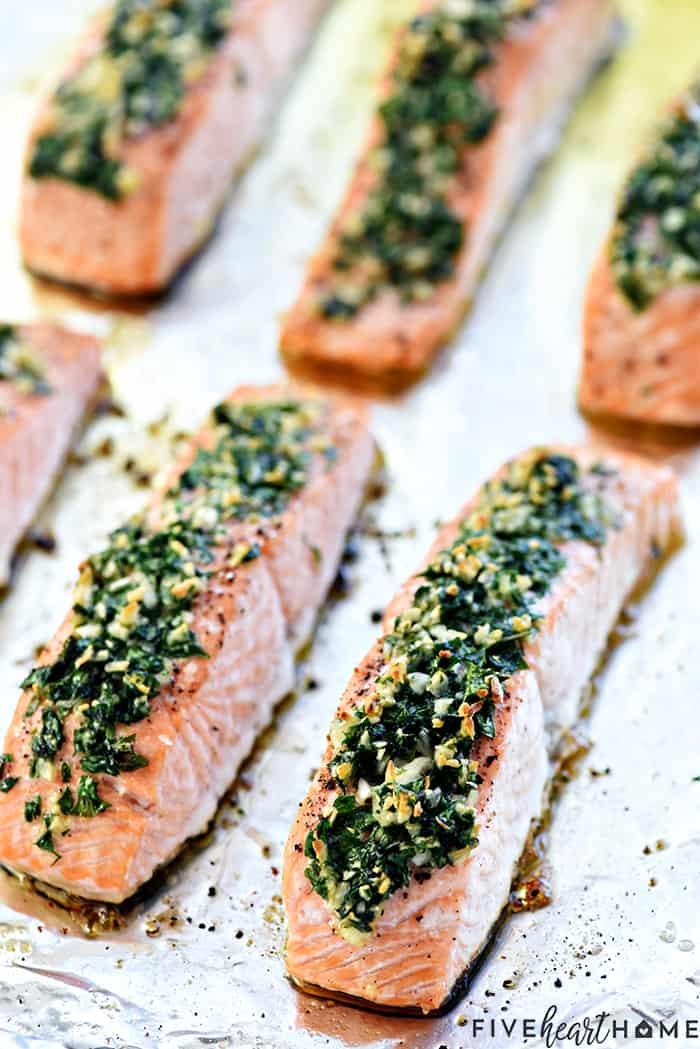 Oven Baked Salmon topped with garlic and parsley on sheet pan.