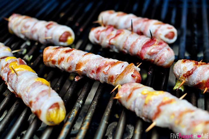 Bacon Wrapped Hot Dogs with Cheese ~ cooked on the grill, this recipe takes a summertime staple to the next level...it's sure to be a hit at any party or barbecue! | FiveHeartHome.com #hotdogs Bacon Wrapped Hot Dogs on the grill