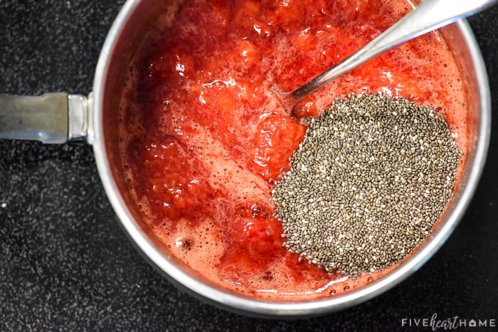 Adding chia seeds to cooked-down strawberries in pot.