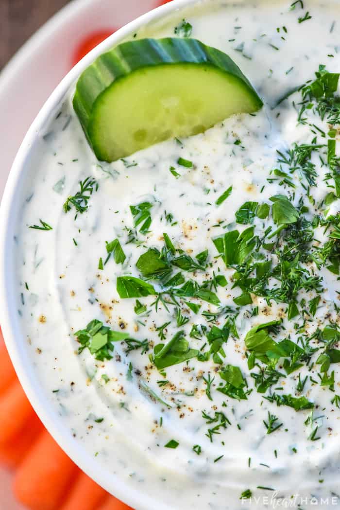 Greek Yogurt Dip close-up with cucumber slice being dipped.