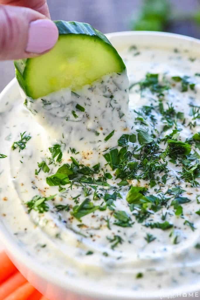 Cucumber slice being dipped into Greek Yogurt Dip.