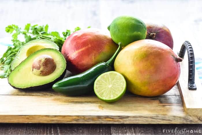 Ingredients to make Mango Avocado Salsa recipe on wooden board.