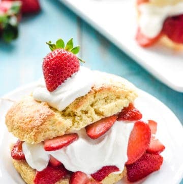 Homemade Strawberry Shortcake on plate topped with whipped cream and berry.