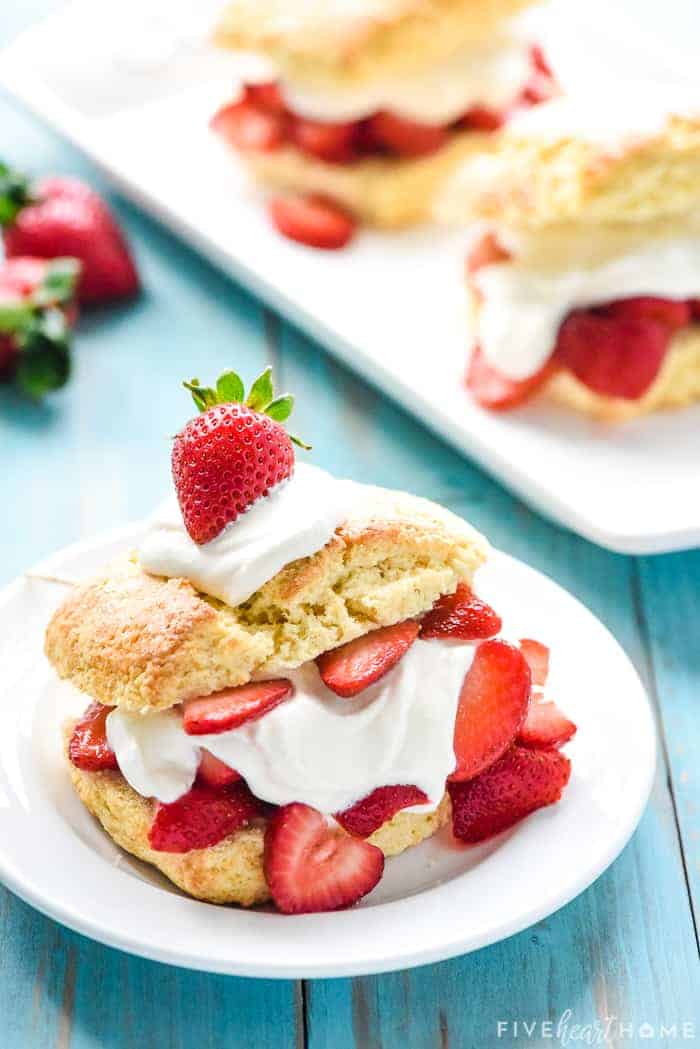 One Homemade Strawberry Shortcake on a small white plate with more in the background.