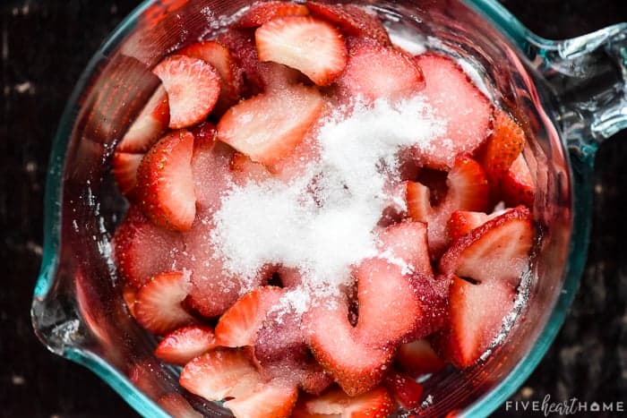 Bowl of sliced strawberries with sugar on top.