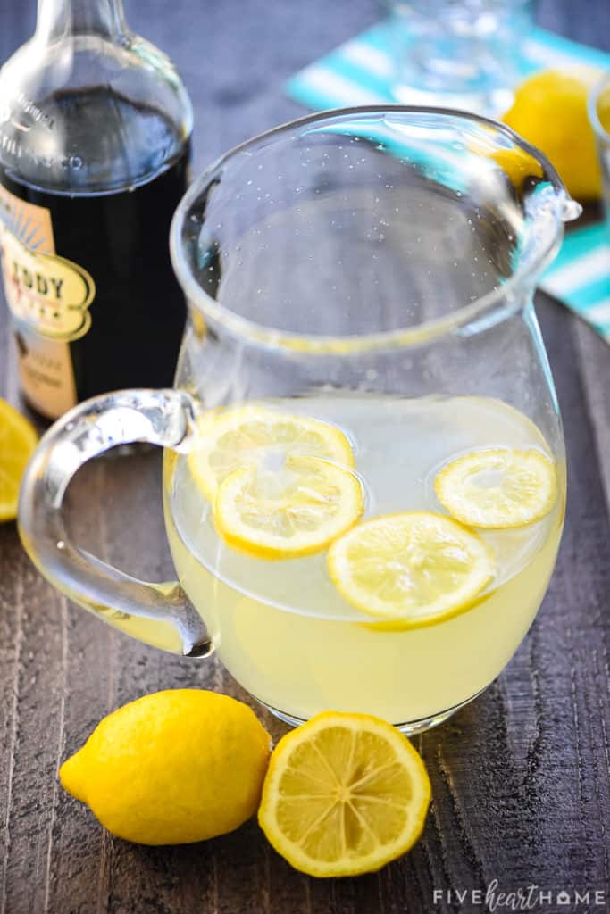 Glass pitcher of lemonade with lemon slices floating in it.
