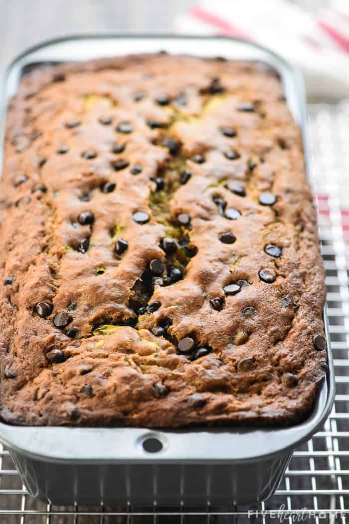 Baked loaf of Zucchini Banana Bread in pan on a cooling rack