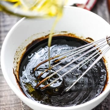 Oil being drizzled into homemade Balsamic Vinaigrette.