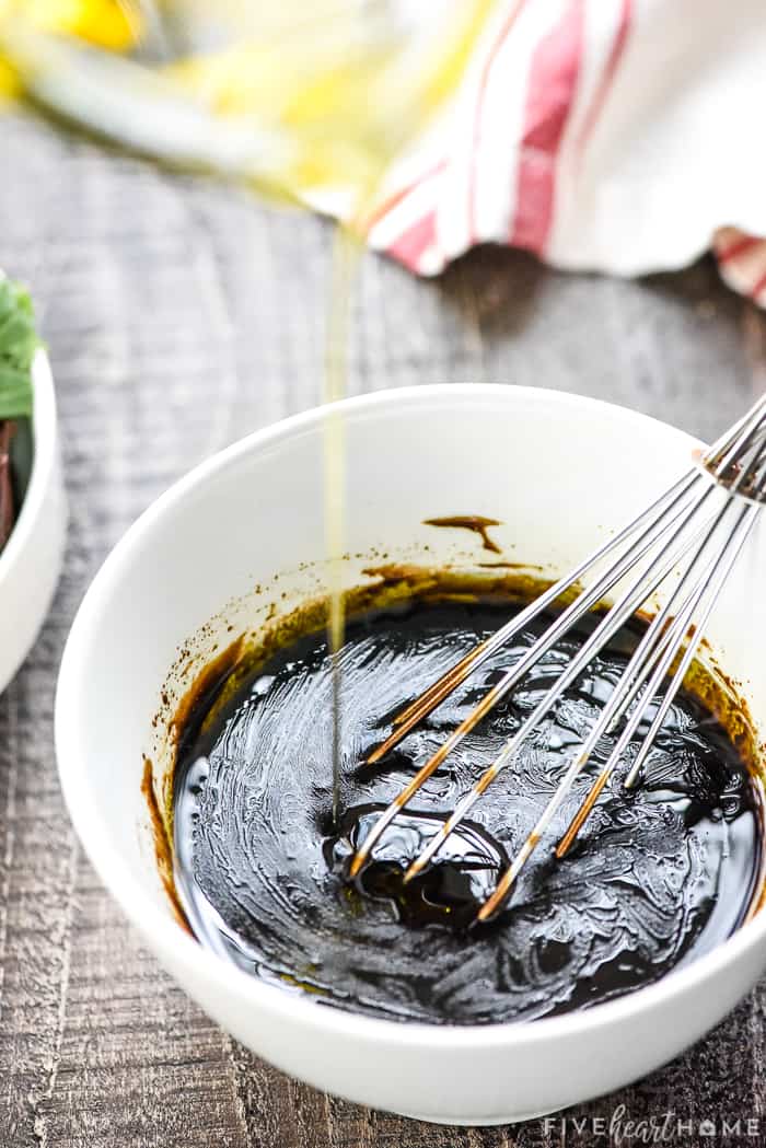 Olive oil being streamed into bowl of whisked ingredients.