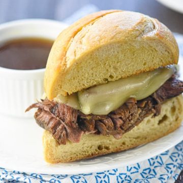 This Slow Cooker French Dip Au Jus recipe features succulent beef slow cooked in a flavorful broth, served on toasty rolls with melted cheese and extra au jus for dipping!