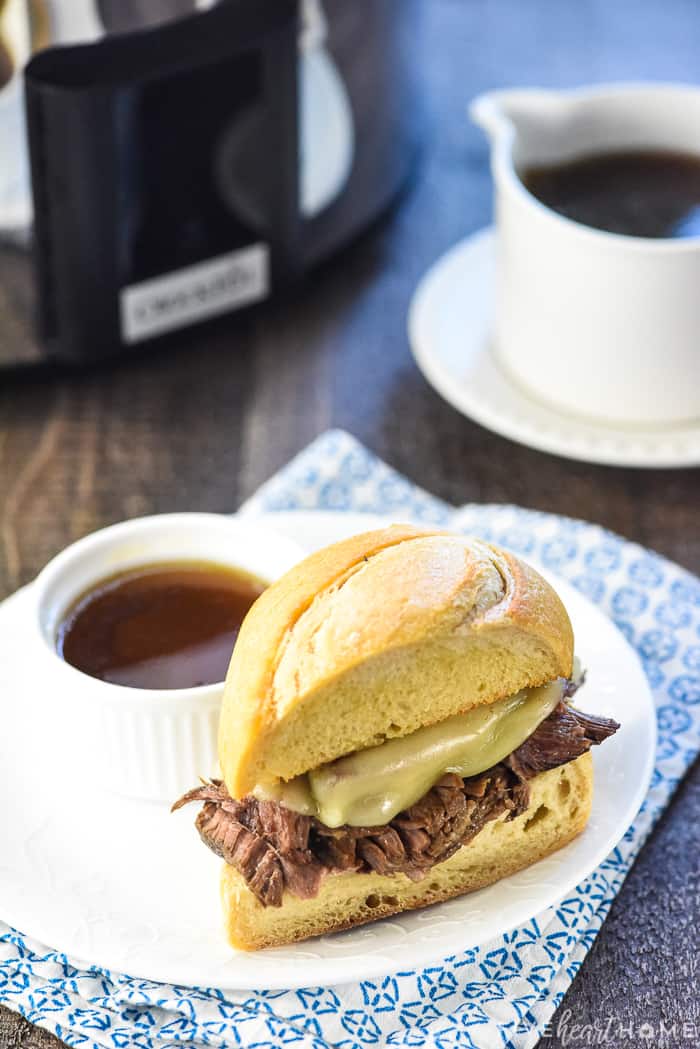 Crock pot French Dip sandwich on plate with au jus for dipping.