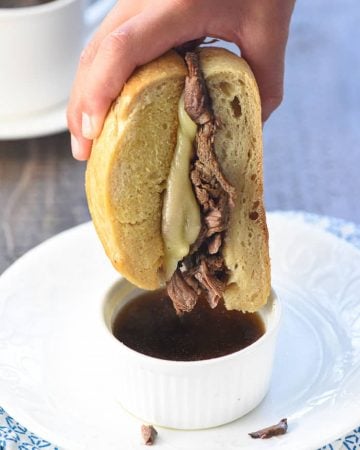 Dipping a Slow Cooker French Dip sandwich into au jus.
