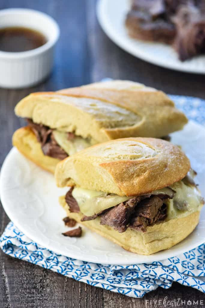Slow Cooker French Dip sandwich on plate with au jus in background.