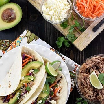 Aerial shot of Slow Cooker Pork Tacos plus garnishes.