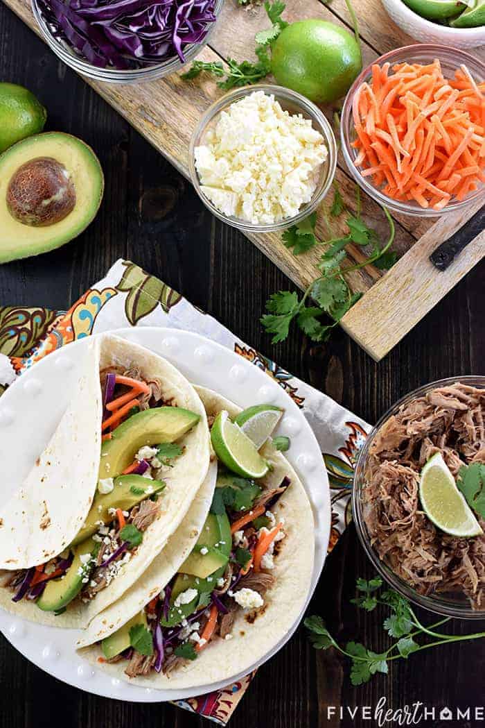 Aerial shot of Slow Cooker Pork Tacos plus garnishes.