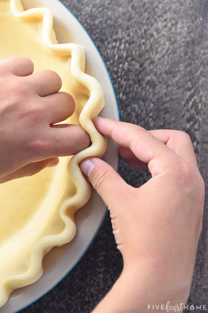 Demonstrating how to flute edges of pie crust.