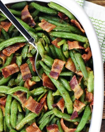 Aerial view of Green Beans with Bacon in a serving dish with spoon.
