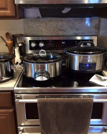 Three slow cookers lined up on kitchen counter and stovetop next to coffee pot