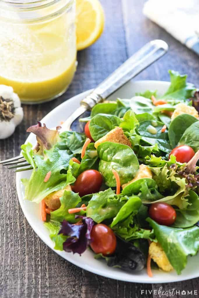 Salad on plate with jar of Champagne Vinaigrette on side.