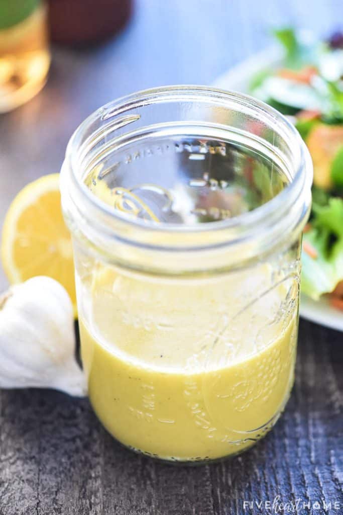 Champagne Vinaigrette recipe in a Mason jar with garlic and lemon.